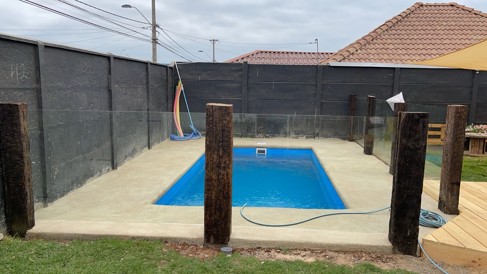 Piscina rectangular pequeña con cercado de madera rústica y vidrio templado